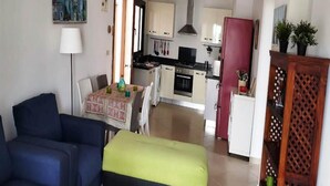A compact living space with a dining area, kitchenette, and a seating area with a sofa and a bench. - Residence Mangle 5332 (Cabo Negro)