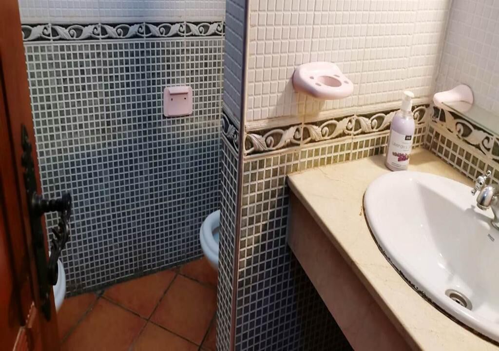 Une salle de bain avec un sol carrelé, un lavabo et des toilettes.