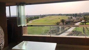 A room with a large window overlooking a grassy area and a distant cityscape.