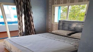 Un dormitorio con cama, ventana con vistas y puerta que da a un balcón.