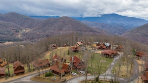 Um refúgio de montanha com várias cabanas, uma estrada sinuosa e vista para as colinas ao redor.