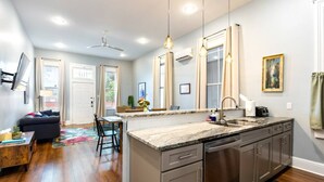 Una cocina moderna con una isla central, electrodomésticos de acero inoxidable y una zona de comedor con sofá y mesa.
