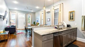 A modern kitchen with a central island, stainless steel appliances, and a dining area with a sofa and table.