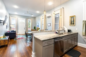 A modern kitchen with a central island, stainless steel appliances, and a dining area with a sofa and table.