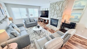 A modern living room with a grey sofa, a beige armchair, a coffee table, and a stone fireplace.
