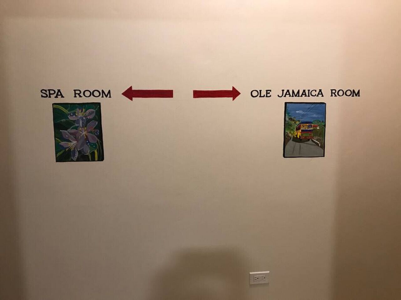 A wall with two signs indicating directions to the spa room and the old Jamaica room, each accompanied by a small picture.