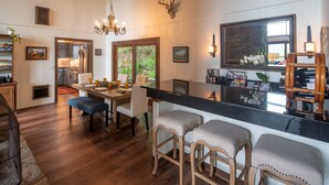 Een ruime keuken met houten vloeren, een eethoek met een groot raam en een bar met krukken.