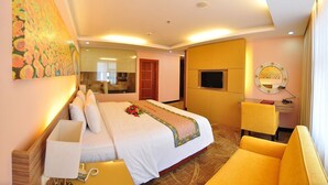 A hotel room with a large bed, a desk with a chair, a TV, and a mirror. - Vietsovpetro Dalat Hotel (Da Lat)