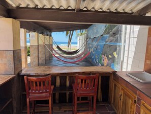 Een houten tafel met twee stoelen, een hangmat en een muurschildering van een strand.