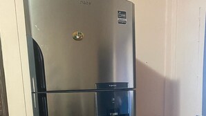 A stainless steel refrigerator with a water dispenser and a logo sticker.