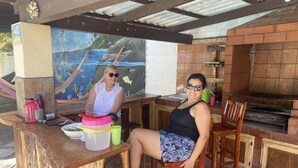 A wooden bar area with a mural of a tropical scene, a grill, and a tiled backsplash.