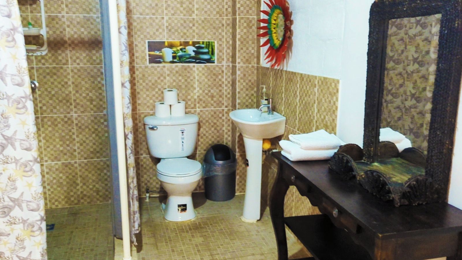 Une salle de bain avec des toilettes, un lavabo et une poubelle.