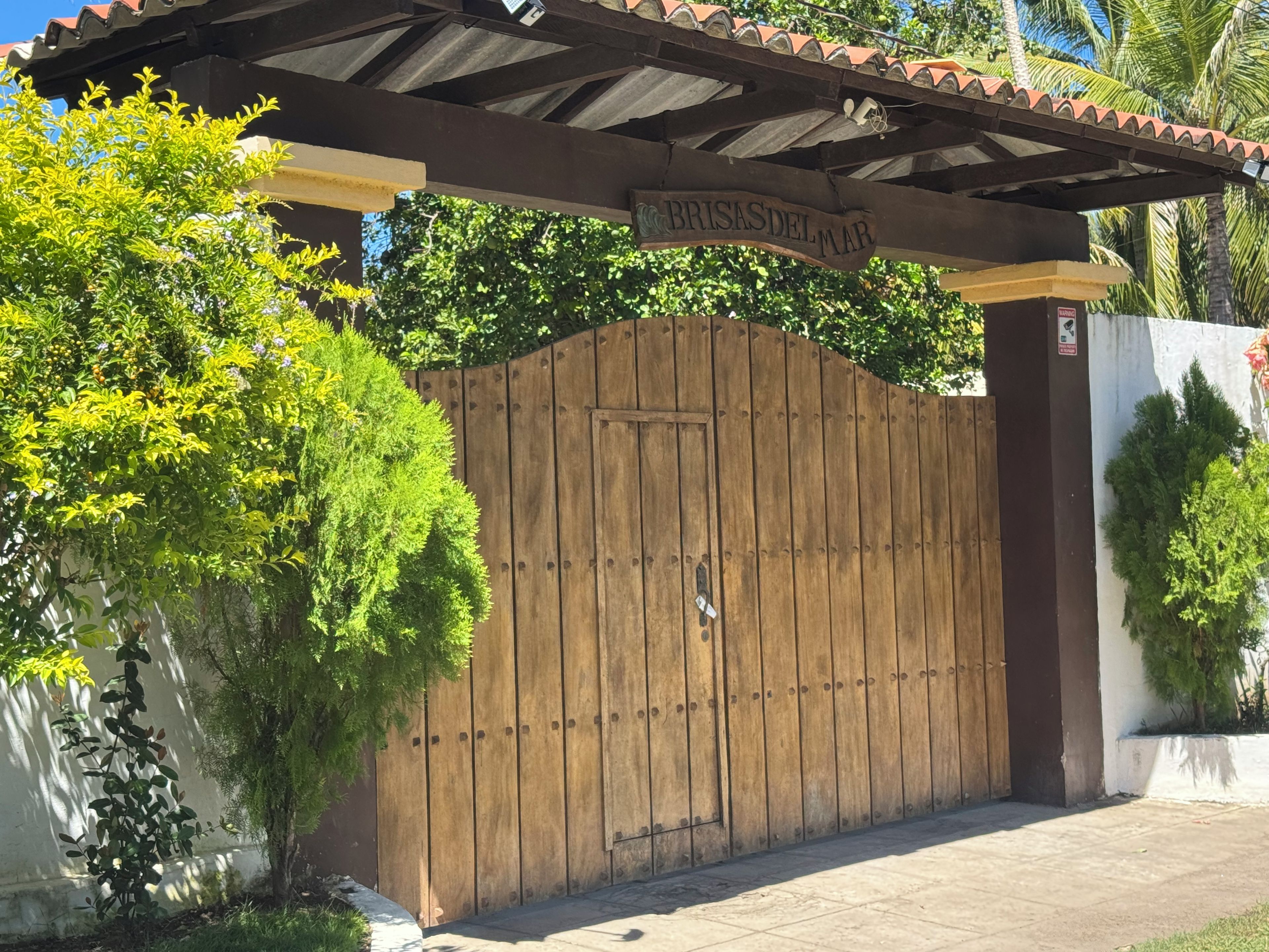 A gated entrance with a wooden gate and a sign above it.