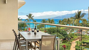 A balcony with a table, chairs, and a bottle of wine.