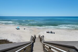 A wooden boardwalk leading to a beach with a clear view of the ocean.