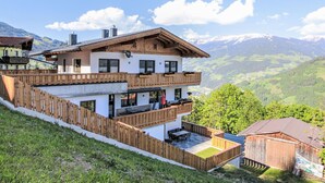 A two-story chalet with a wooden balcony, a patio area, and a mountain view. - Apartment Dengg by Interhome (Hippach)