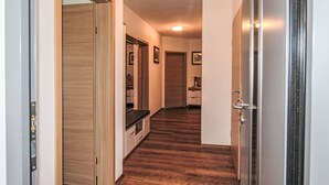 A hallway with wooden flooring, a kitchen area with cabinets and a countertop, and a door leading to another room. - Apartment Dengg by Interhome (Hippach)