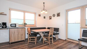 A compact kitchen with a dining area, wooden cabinets, a microwave, and a coffee maker. - Apartment Dengg by Interhome (Hippach)