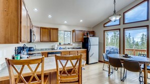 Une cuisine moderne avec des meubles en bois, un réfrigérateur et un coin repas comprenant une table et des chaises.