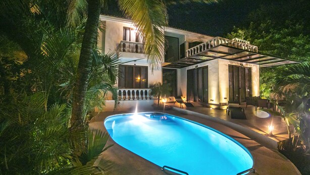 Ein modernes Haus mit Swimmingpool, umgeben von üppigem Grün.