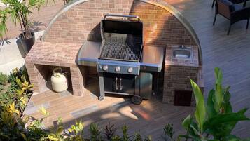 An outdoor kitchen with a grill, a sink, and a gas tank.