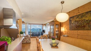 A modern kitchen with a large island, wooden accents, and a view of mountains. - Vacation Home "Haus der Sinne Bregenzerwald" with Mountain View & Balcony (Egg-Kaltenbrunnen)