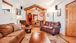 A living room with a wooden ceiling, a dining table, and two leather sofas.