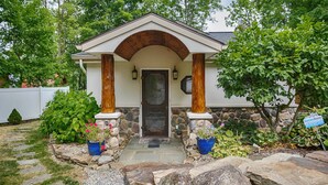 A house with a stone foundation, a wooden porch with columns, and a front door.