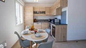 Una cocina moderna con armarios de madera, una mesa de comedor con sillas y una pequeña isla con microondas y tostadora.