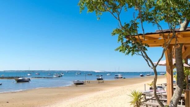 A beach with boats, a wooden structure, and a clear sky.
