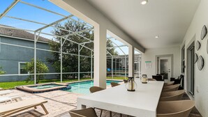 A covered outdoor patio with a pool, dining table, and chairs. - Themed Games, Theater Room | Screened Pool Area (Davenport)