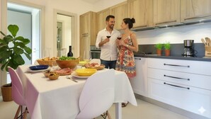 A modern kitchen with wooden cabinets, a dining table set with food and drinks, and a potted plant. - Residenza Cantalupo – Relax Oasis with PoolAp37 (Imperia)