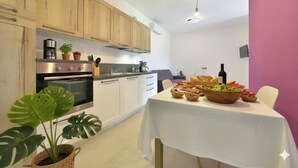 A modern kitchen with wooden cabinets, stainless steel appliances, and a dining table set with food. - Residenza Cantalupo – Relax Oasis with PoolAp37 (Imperia)