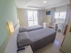 Une chambre d’hôtel avec deux lits, un bureau, une chaise et une fenêtre.