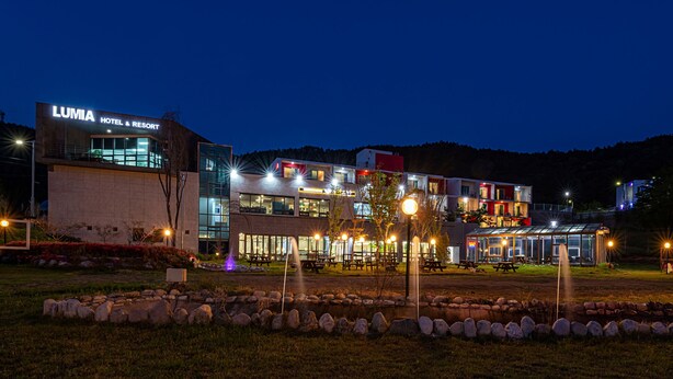 A hotel with a modern design, featuring a prominent sign, outdoor seating, and a well-lit entrance.