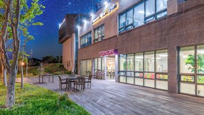 A modern building with a 'FOOD & CAFE' sign, outdoor seating, and a starry night sky.