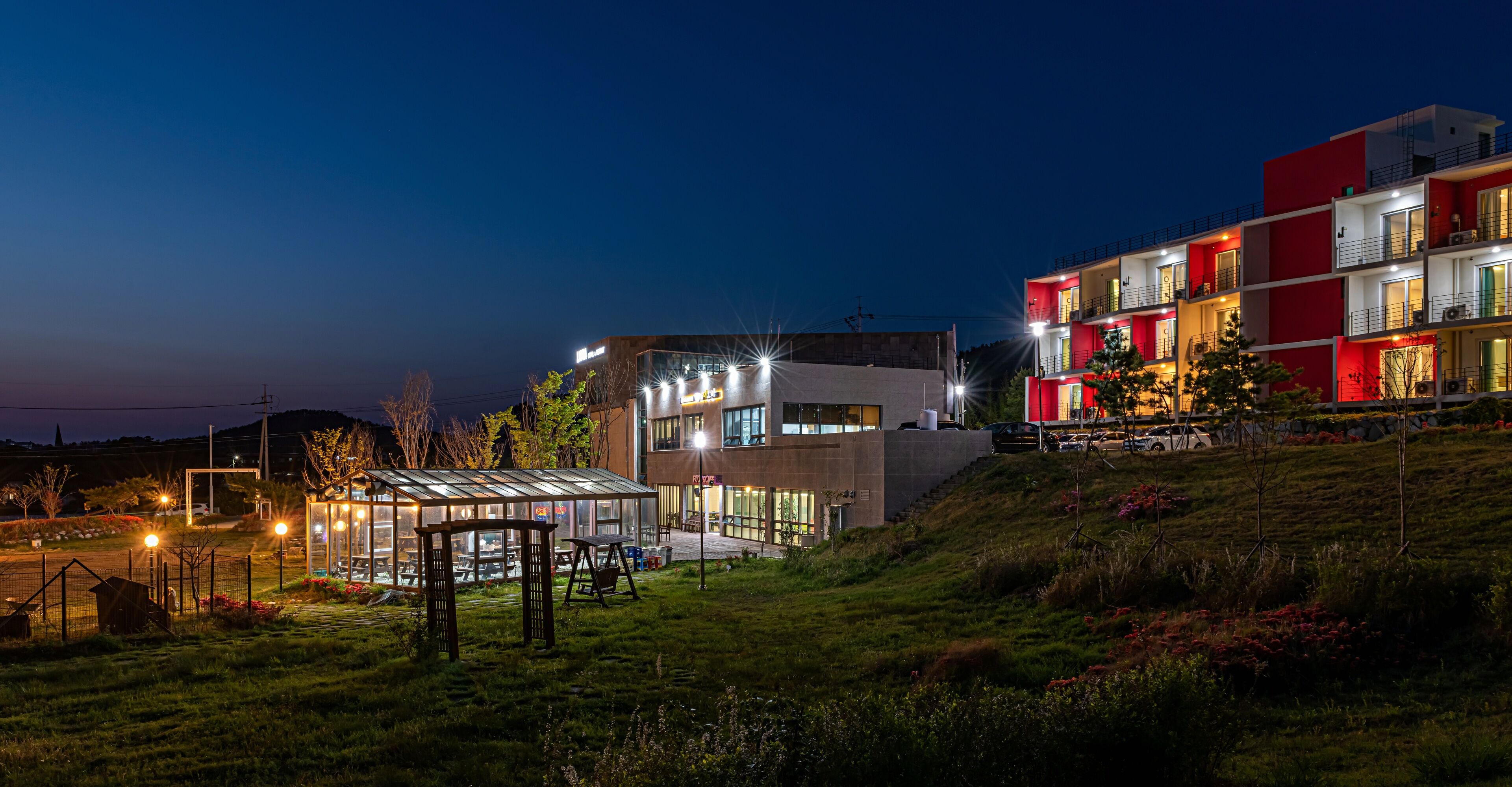 A modern building with a glass conservatory, a covered outdoor seating area, and a red and white facade.