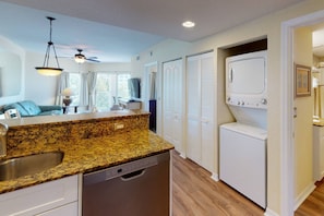 A compact kitchen with granite countertops, a dishwasher, a built-in oven, and a ceiling fan.