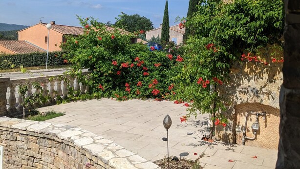 Ein Innenhof mit Steinmauern, einer Fontäne und roten Blumen.