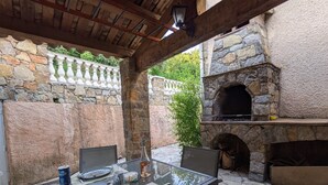 Eine Terrasse im Freien mit einer Steinmauer, einem Glastisch und einem Kamin aus Stein.