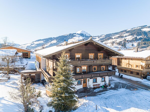 A large wooden chalet with multiple balconies and a snow-covered landscape in the background. - Holiday home on former farm (Brixen im Thale)