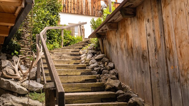 A wooden staircase with a rustic design, leading up to a building with a wooden facade.