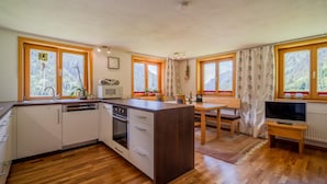 A compact kitchen with a microwave, oven, and sink. There is a dining area with a table and chairs.