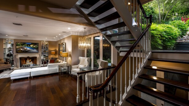 Ein geräumiges Wohnzimmer mit Kamin, Treppe und Blick ins Grüne.