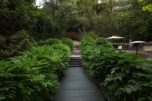 Stroll along the garden pathway to a serene seating area under two shaded umbrellas.