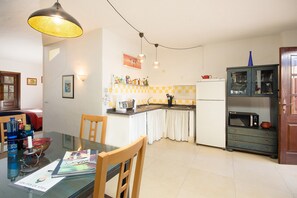 A compact kitchen with a dining table, chairs, a microwave, and a cabinet.