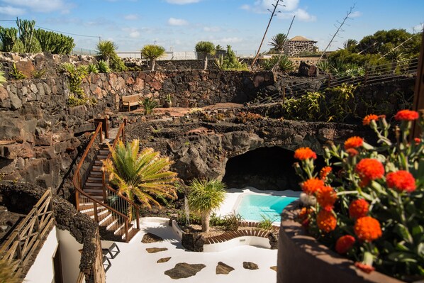 A pool area with a stone wall, a wooden staircase, and a bench.