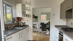 Et moderne køkken med hvide skabe, en gasovn og et spiseområde med et bord og stole.