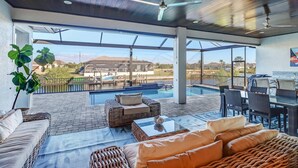 Une vaste terrasse extérieure avec une piscine, des meubles en osier et une vue sur un terrain de golf.