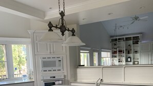 A modern kitchen with white cabinetry, a large island with stools, and a ceiling fan. - 80-acre Mountaintop Villa with Spectacular Views (Coarsegold)